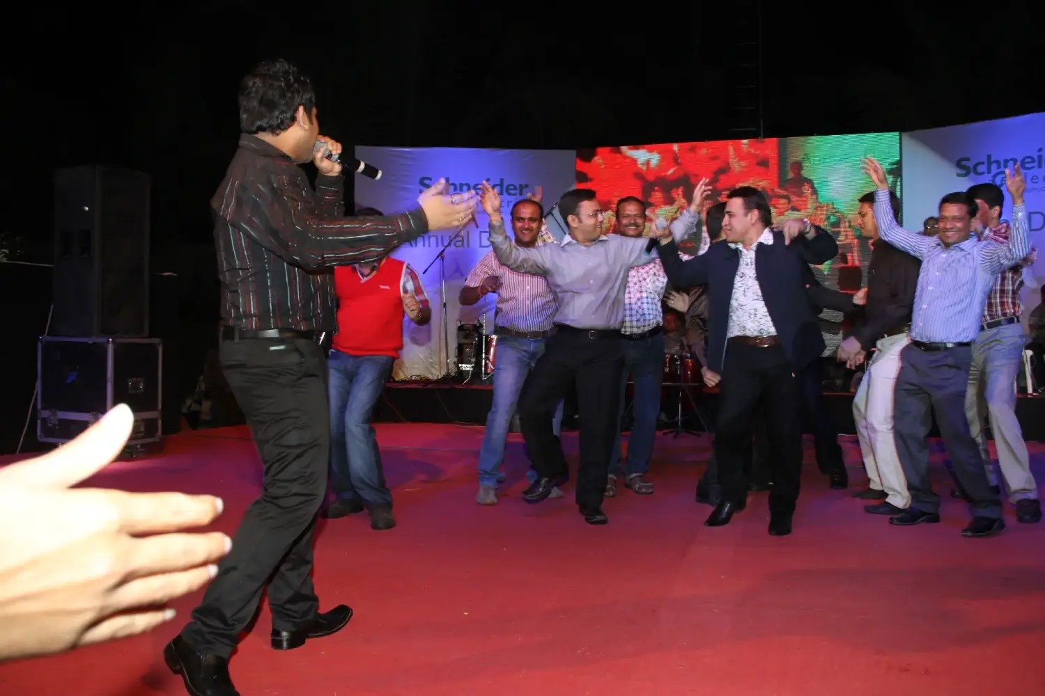 Man and woman speaking on stage at night with blue lighting